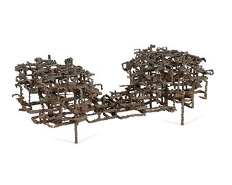 A sculptural arrangement of interwoven metal rods forming two blocky forms connected by a bridge.