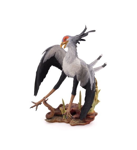 A detailed figurine of a grey bird with black wings and a red head crest standing on a rocky base.