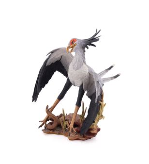 A realistic sculpture of a grey bird with black wings and a red face, standing on a base with a snake.