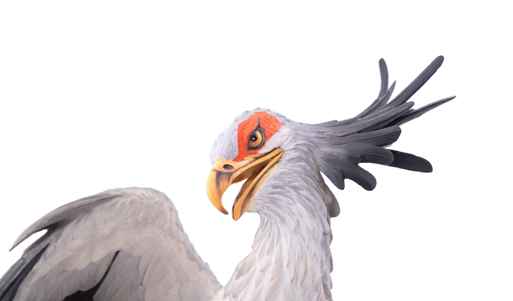 A realistic sculpture of a grey bird with black wings and a red face, standing on a base with a snake.