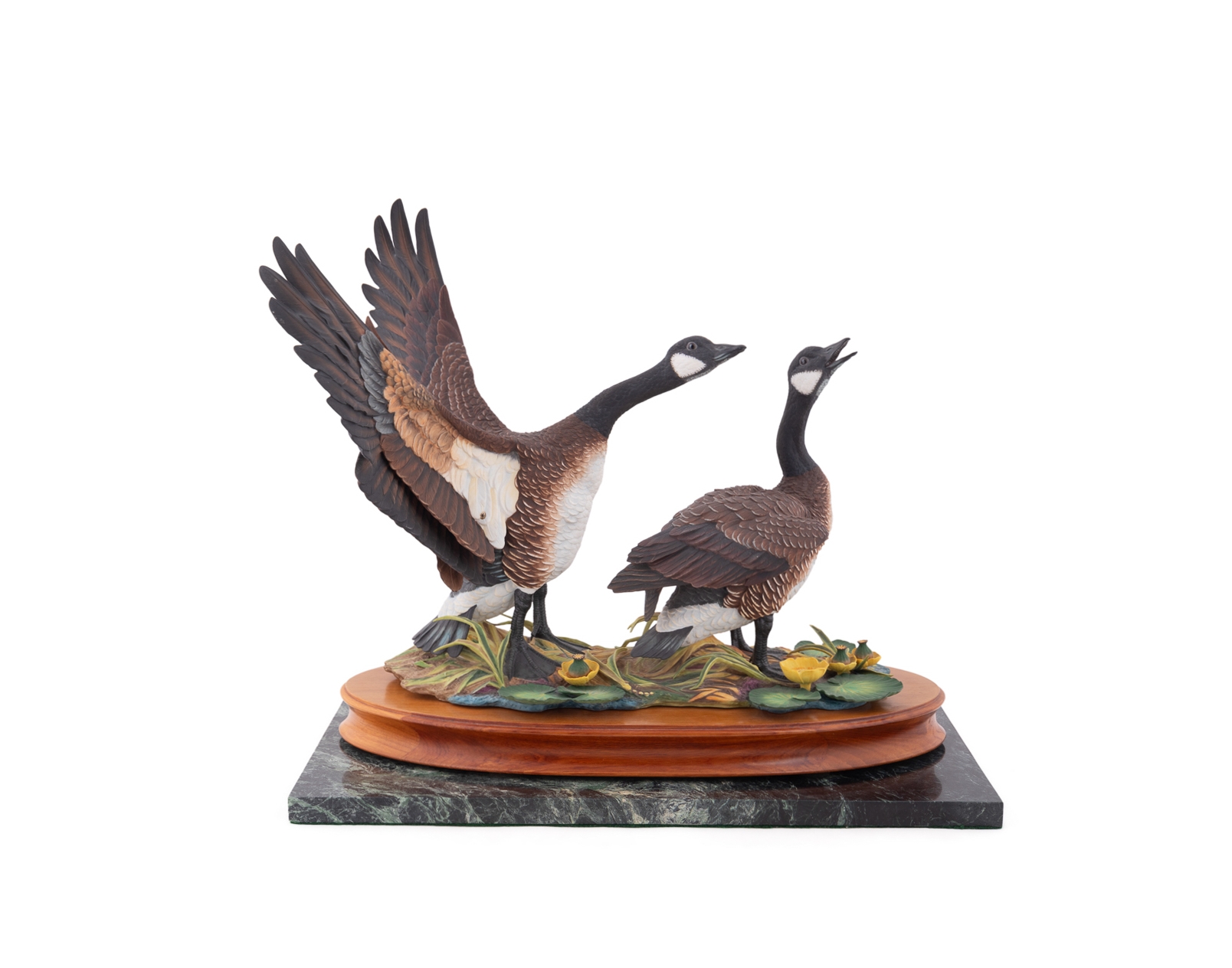 A sculptural diorama featuring two geese on a lily pad base.