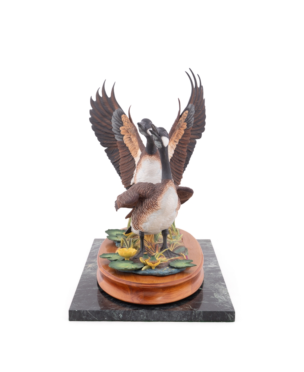 A sculptural diorama featuring two geese on a lily pad base.