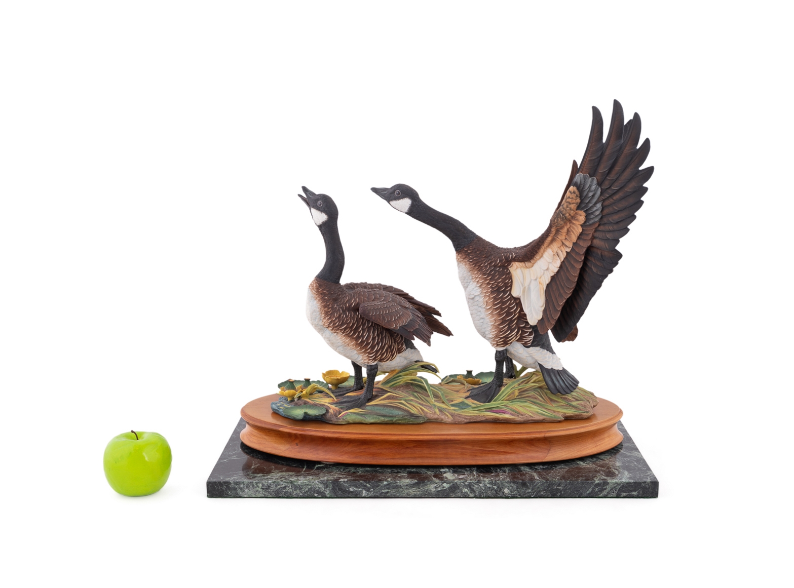 A sculptural diorama featuring two geese on a lily pad base.