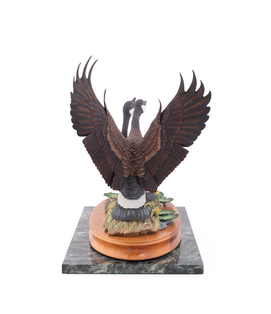 A sculptural diorama featuring two geese on a lily pad base.