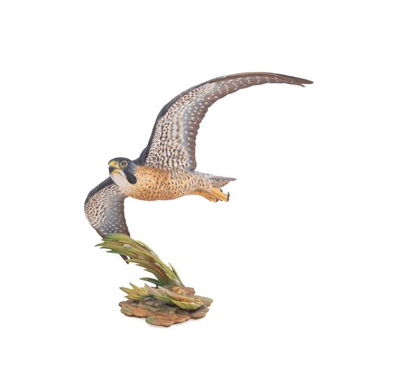 A realistic sculpture of a bird in flight perched on a textured base.