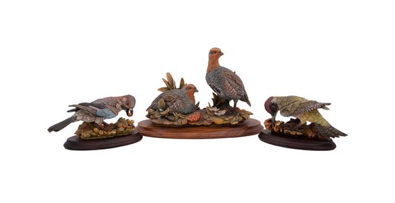 A set of four sculpted birds displayed on individual wooden bases.