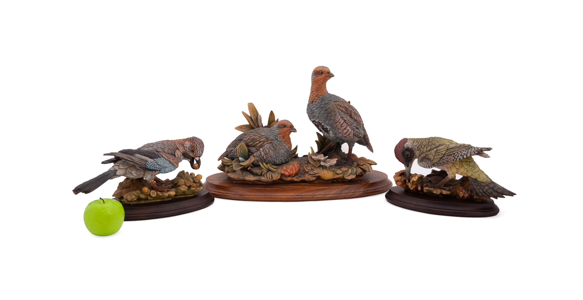 A set of four sculpted birds displayed on individual wooden bases.