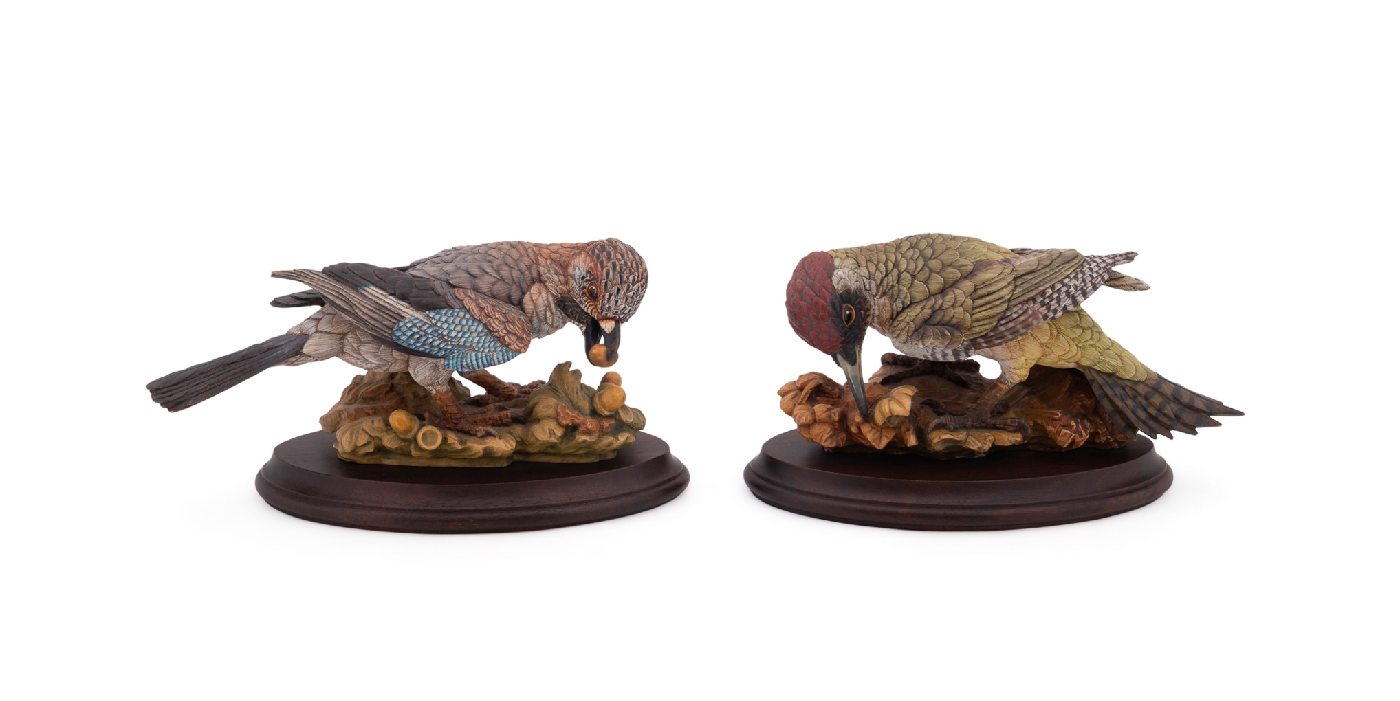 A set of four sculpted birds displayed on individual wooden bases.