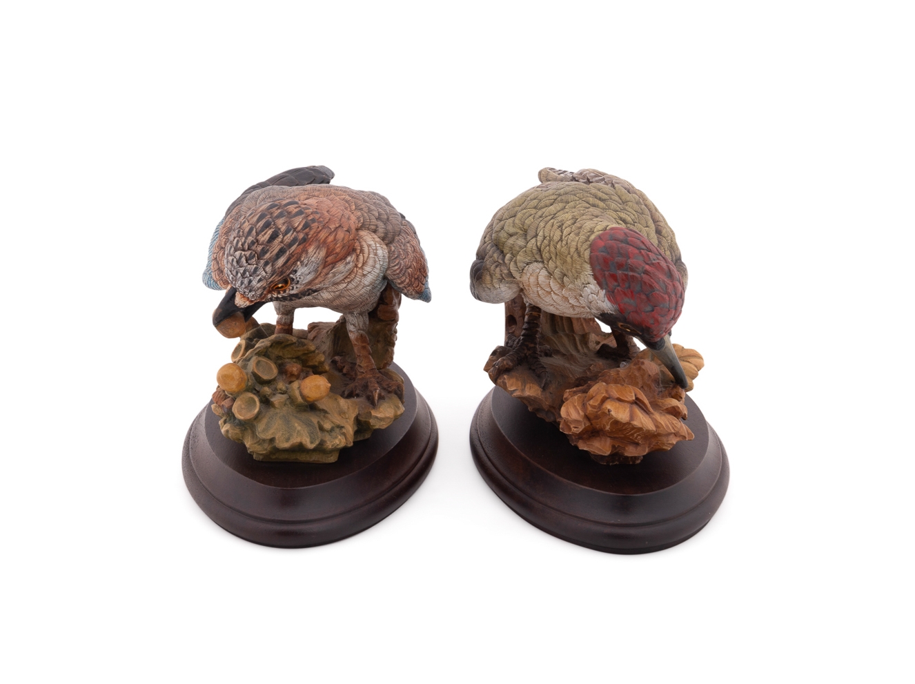A set of four sculpted birds displayed on individual wooden bases.