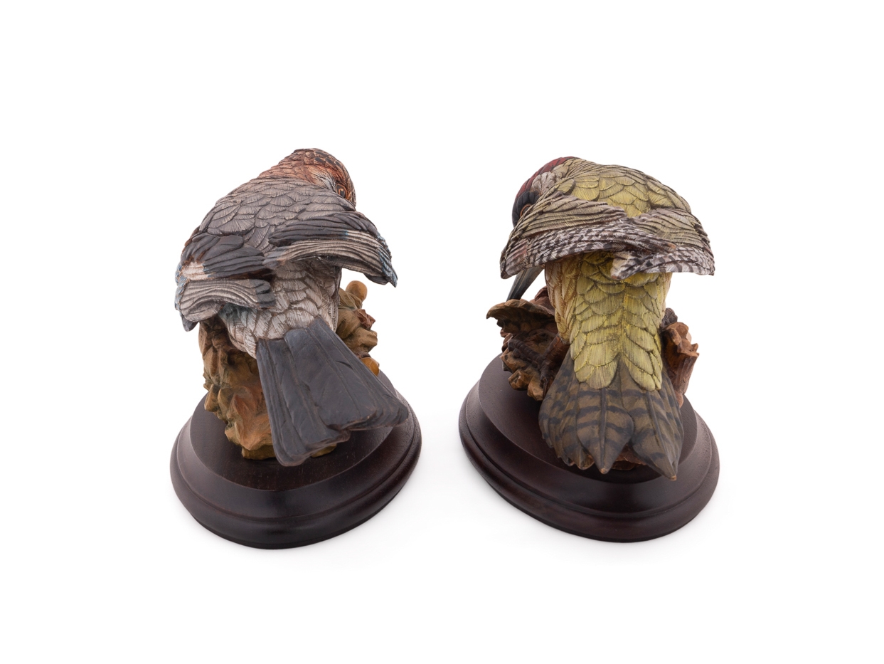 A set of four sculpted birds displayed on individual wooden bases.