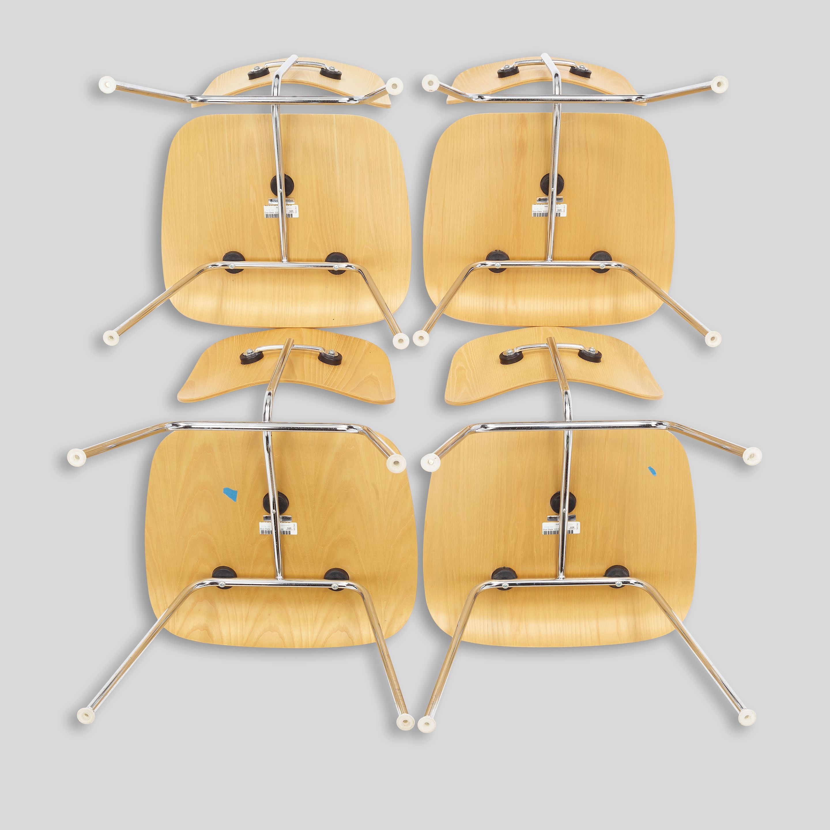 A minimalist interior scene featuring a round wooden table surrounded by four matching chairs.
