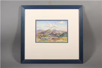 A framed landscape painting of a mountain valley with small buildings and a blue sky.