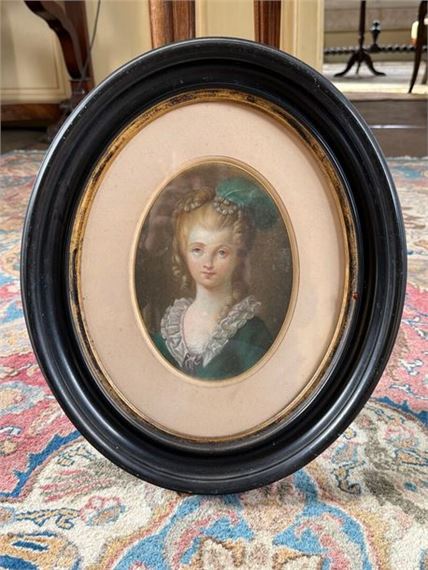 A framed miniature portrait of a young woman in period attire.