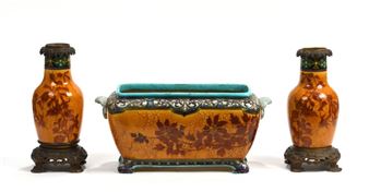 A trio of ornate ceramic vessels featuring floral motifs and metallic accents.