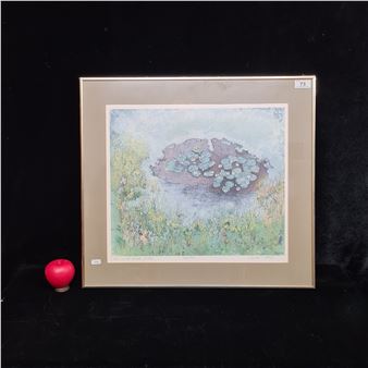 A framed watercolor print of a pond with lily pads and wildflowers, displayed next to a red apple.
