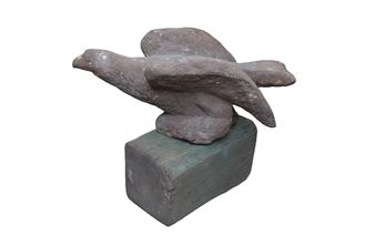 A sculptural figure of a bird in flight perched atop a rectangular block.