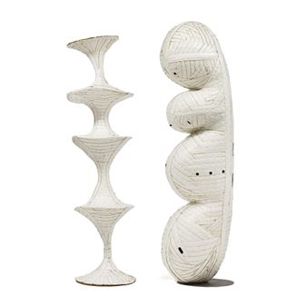 A pair of white ceramic sculptures featuring organic, stacked forms against a stark background.