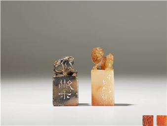 A minimalist display of two carved stone seals featuring animal figures and Chinese characters.