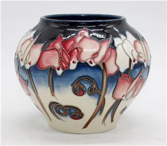 A ceramic vase featuring a stylized floral design with pink and white blossoms against a dark blue background.