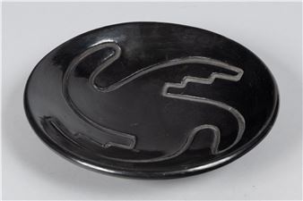 A glossy black oval dish featuring a raised, stylized animal silhouette in silver-toned metal.
