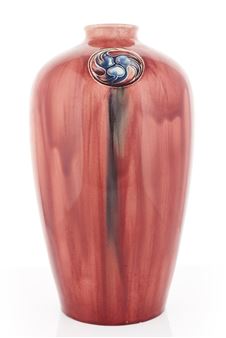 A glossy reddish-brown vase with a decorative circular medallion featuring blue and black abstract forms.