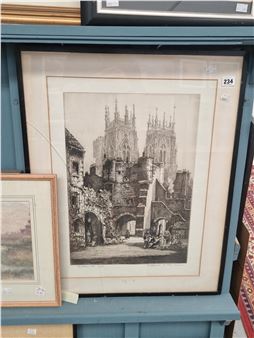 A framed etching of a historic European town square featuring a grand cathedral and stone archways.