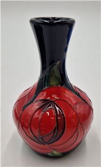 A glossy ceramic vase featuring a bold red rose design against a deep navy background.