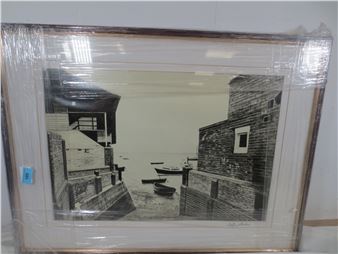 A black-and-white framed print of a quiet harbor scene with brick buildings and moored boats.