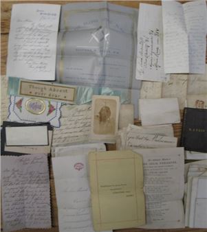 A scattered collection of vintage letters, cards, and documents arranged on a wooden surface.