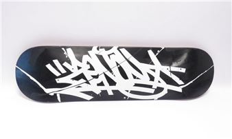 A black skateboard deck featuring a white graffiti-style tag against a plain background.