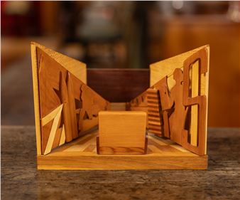 A wooden architectural model featuring intricate cutouts and layered geometric forms.
