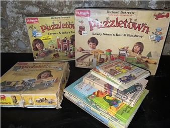 A collection of colorful board game boxes and rulebooks stacked on a dark surface.