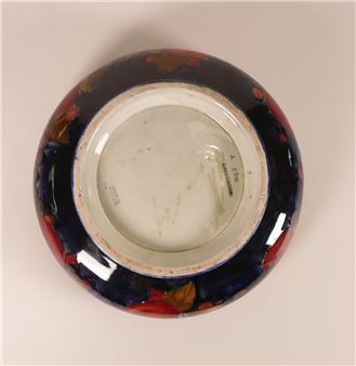 A top-down view of a ceramic bowl with a dark blue exterior and floral pattern, revealing its white interior base.
