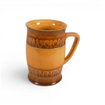 A textured ceramic mug with embossed lettering and a warm amber glaze.