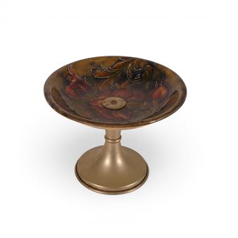 A decorative pedestal bowl featuring a floral design on a dark, glossy surface.