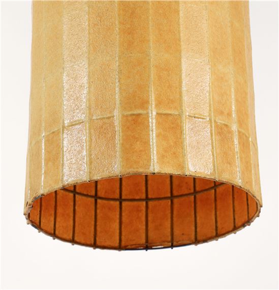 A close-up of a cylindrical lamp shade with vertical pleats and a visible wire frame.