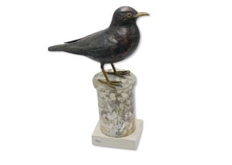 A black bird sculpture perched on a weathered stone pedestal.