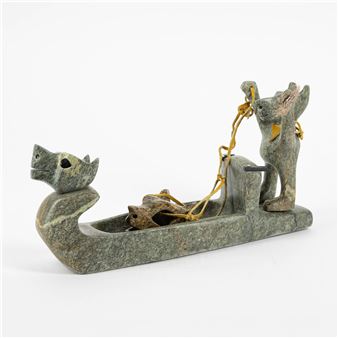 A carved stone sculpture of a dog pulling a boat with a fox inside.