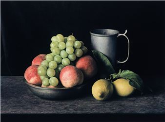 A dark still life featuring a bowl of fruit, lemons, and a metal pitcher against a black background.