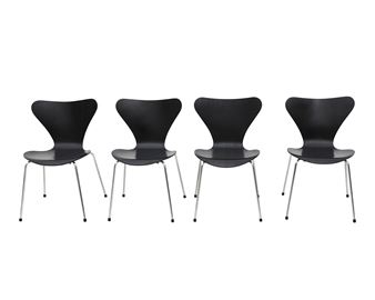 A minimalist product shot of four identical black chairs arranged in a row against a stark white background.