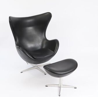 A sleek black lounge chair and ottoman set against a stark white background.