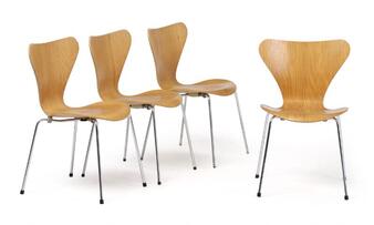 A set of four light wood chairs with curved backs and metal legs arranged against a white background.