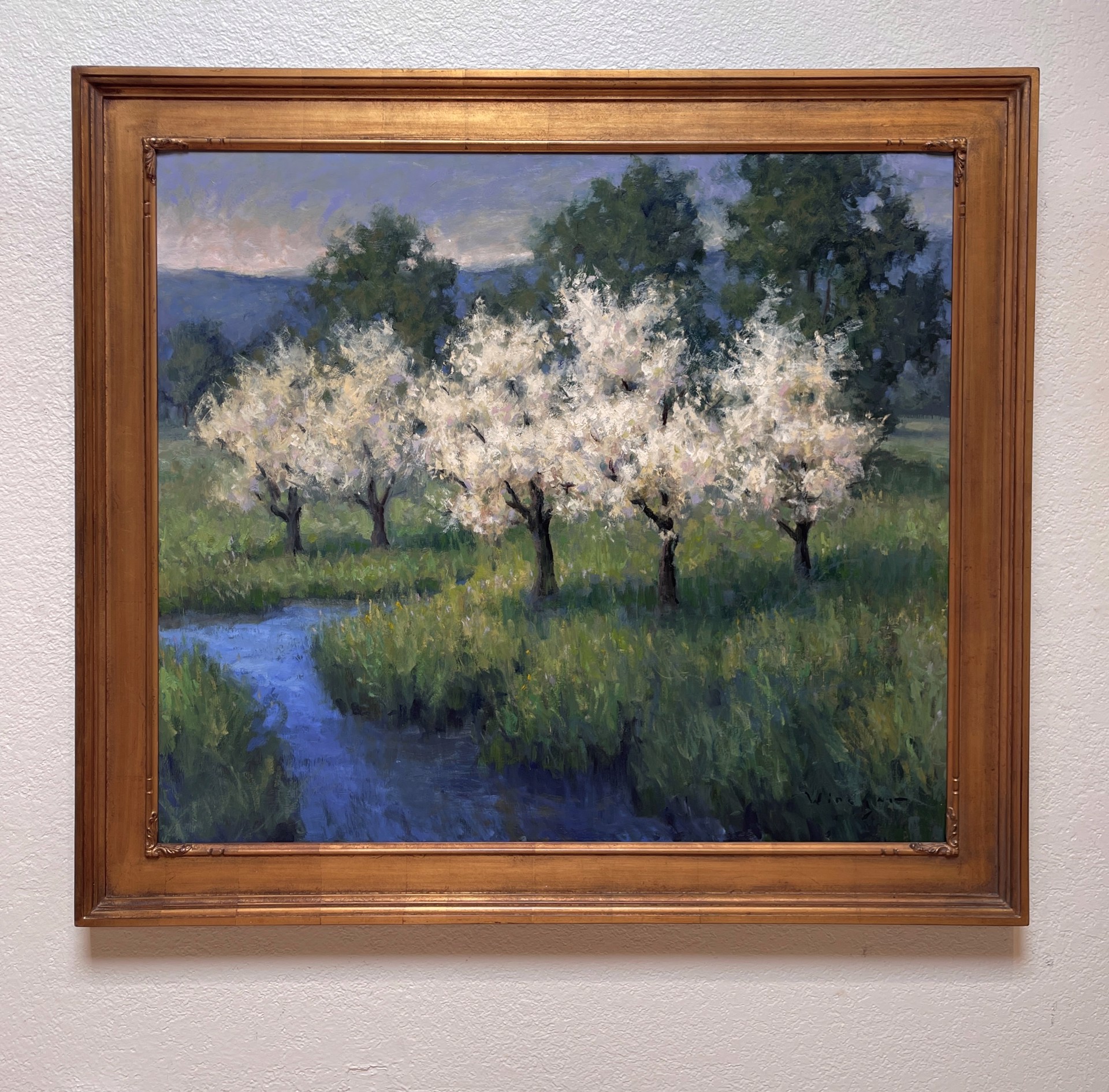 A serene landscape painting of blossoming trees beside a stream.