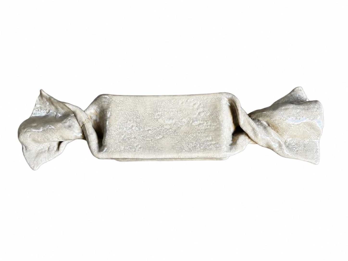 A ceramic sculpture shaped like a wrapped candy with a crackled glaze texture.