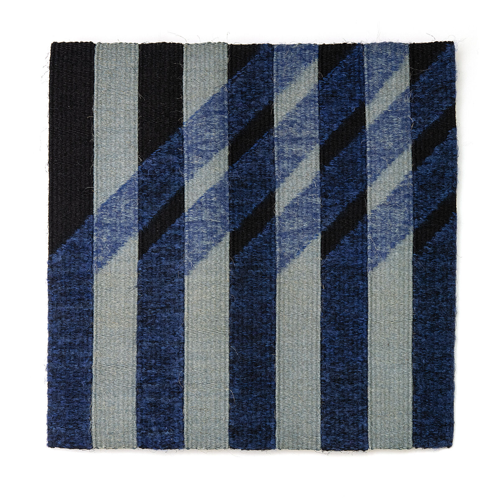 A textile artwork featuring vertical ribbons of blue and grey fabric with diagonal stitching patterns.