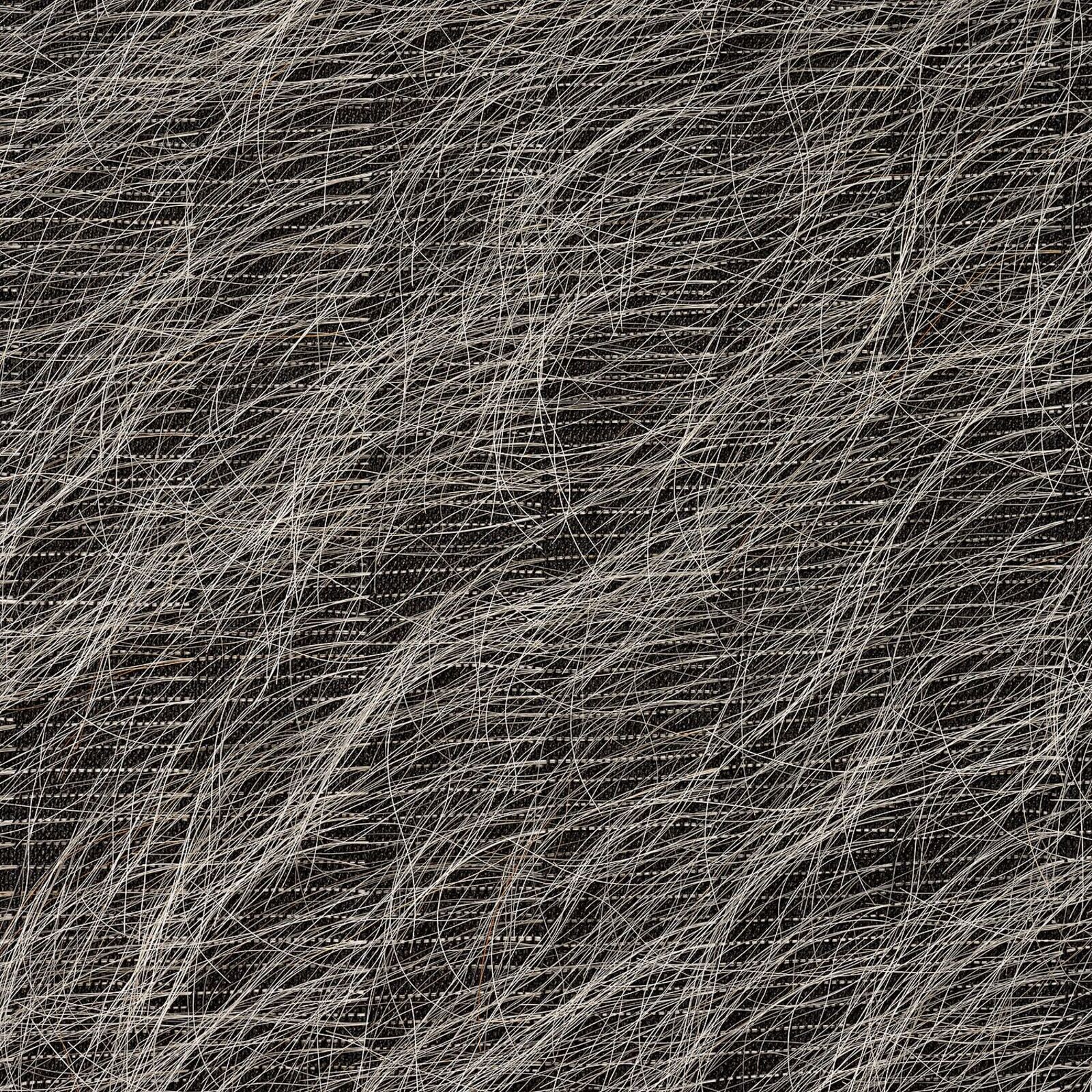 A textured textile artwork featuring a city skyline silhouette at the bottom, displayed on a white wall.