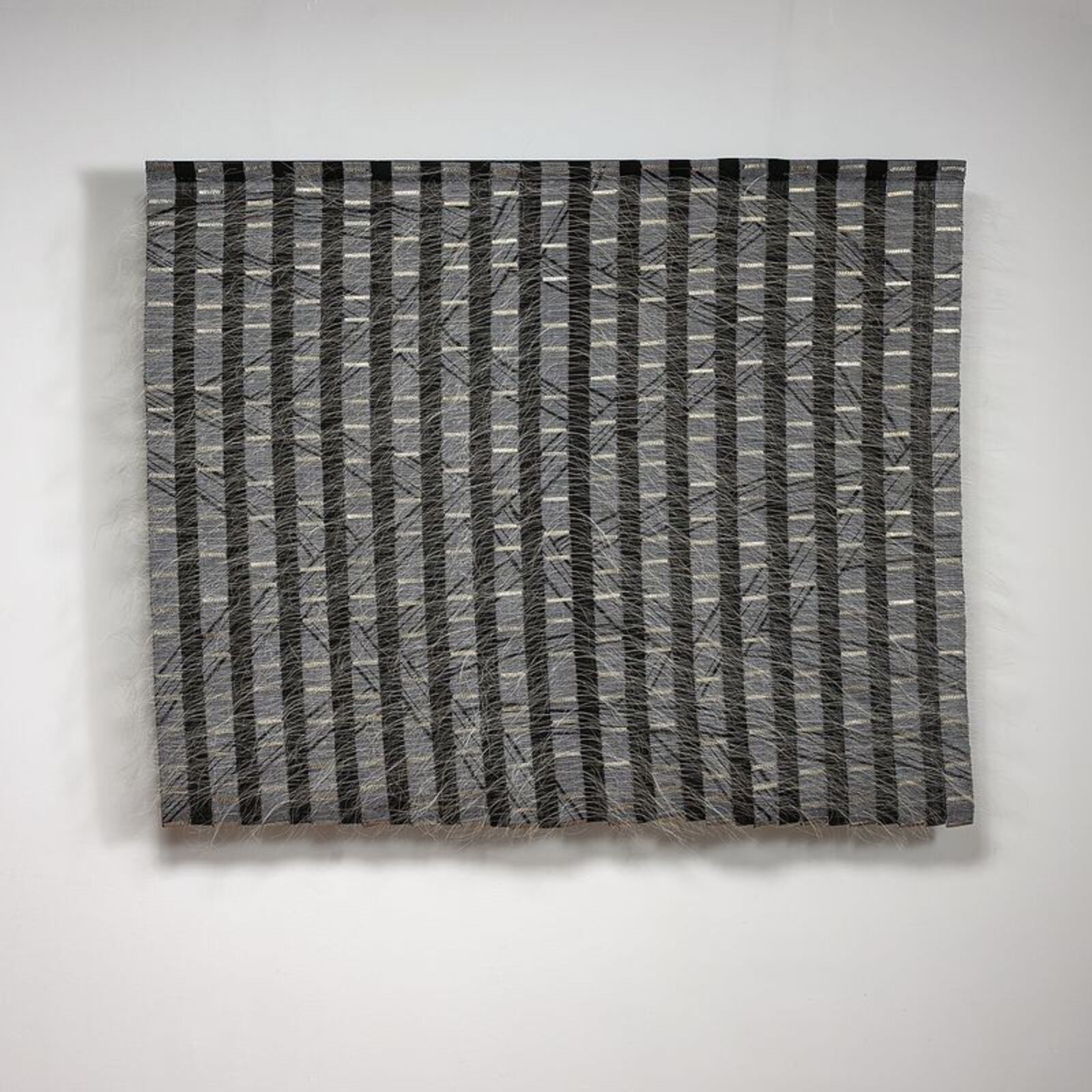A monochromatic textile artwork featuring vertical stripes and diagonal lines.