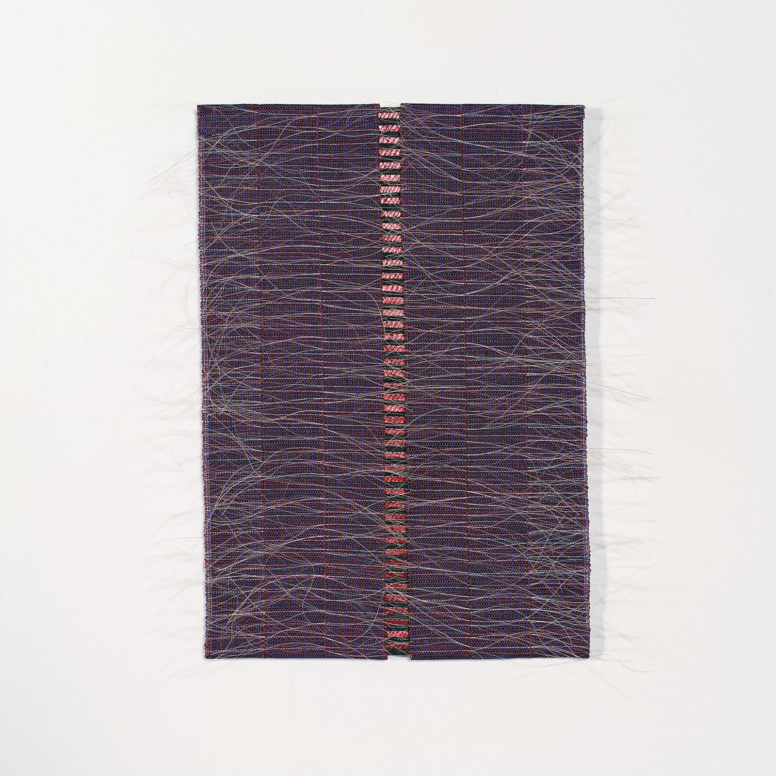 A rectangular textile piece featuring a central vertical seam with red and black threads against a dark woven background.