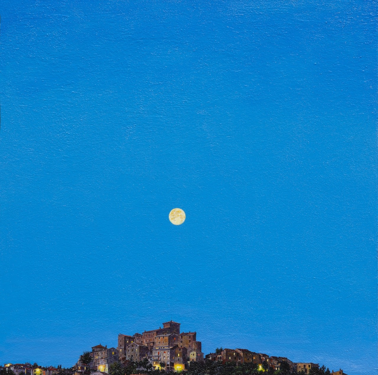 A full moon rises over a small town at night.