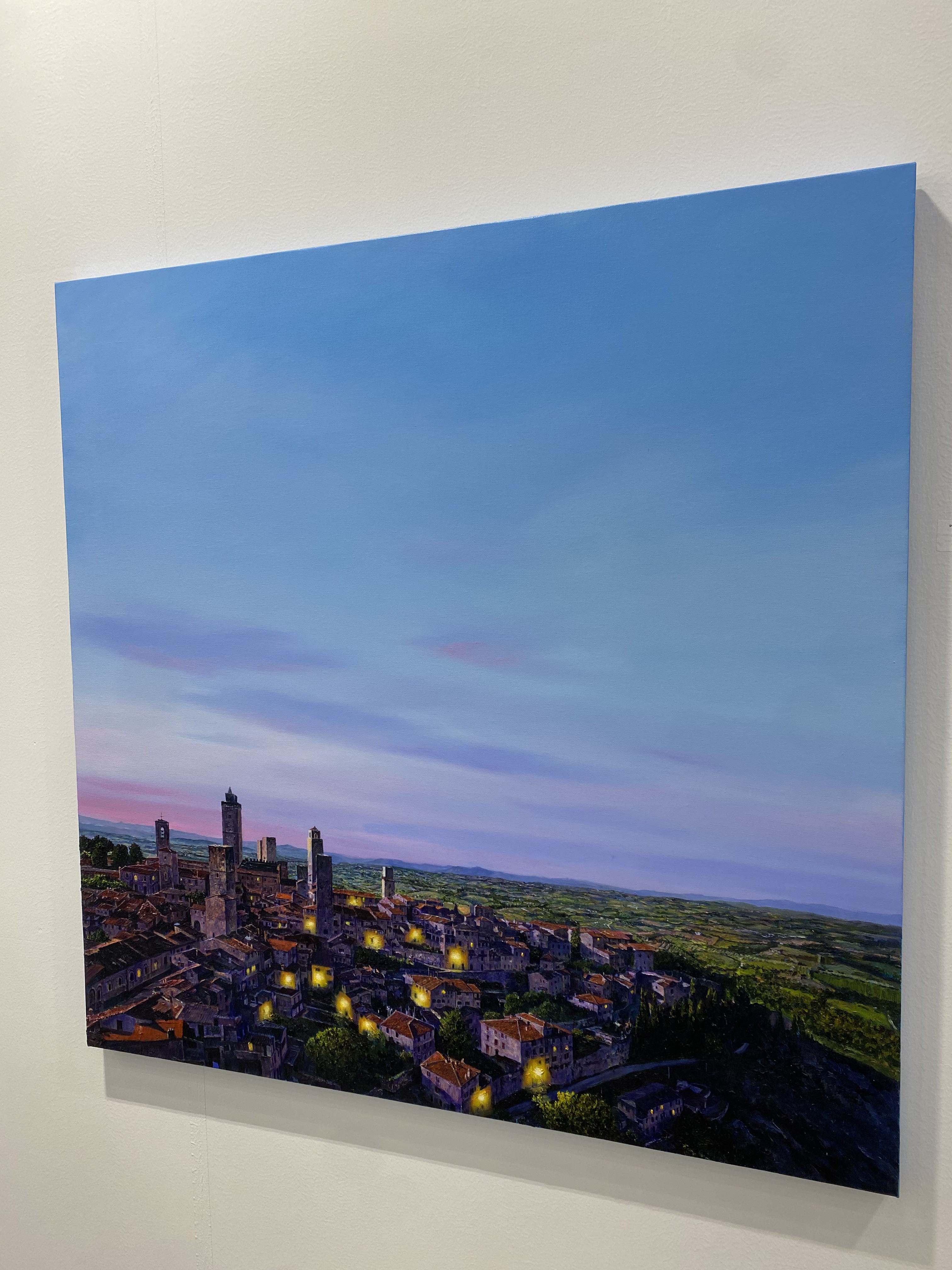 A painting of a city at dusk with a blue sky.
